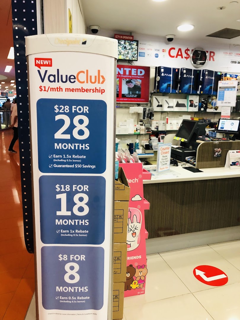 A promotional stand for ValueClub membership at the entrance of an electronics store, with the counter and products visible.