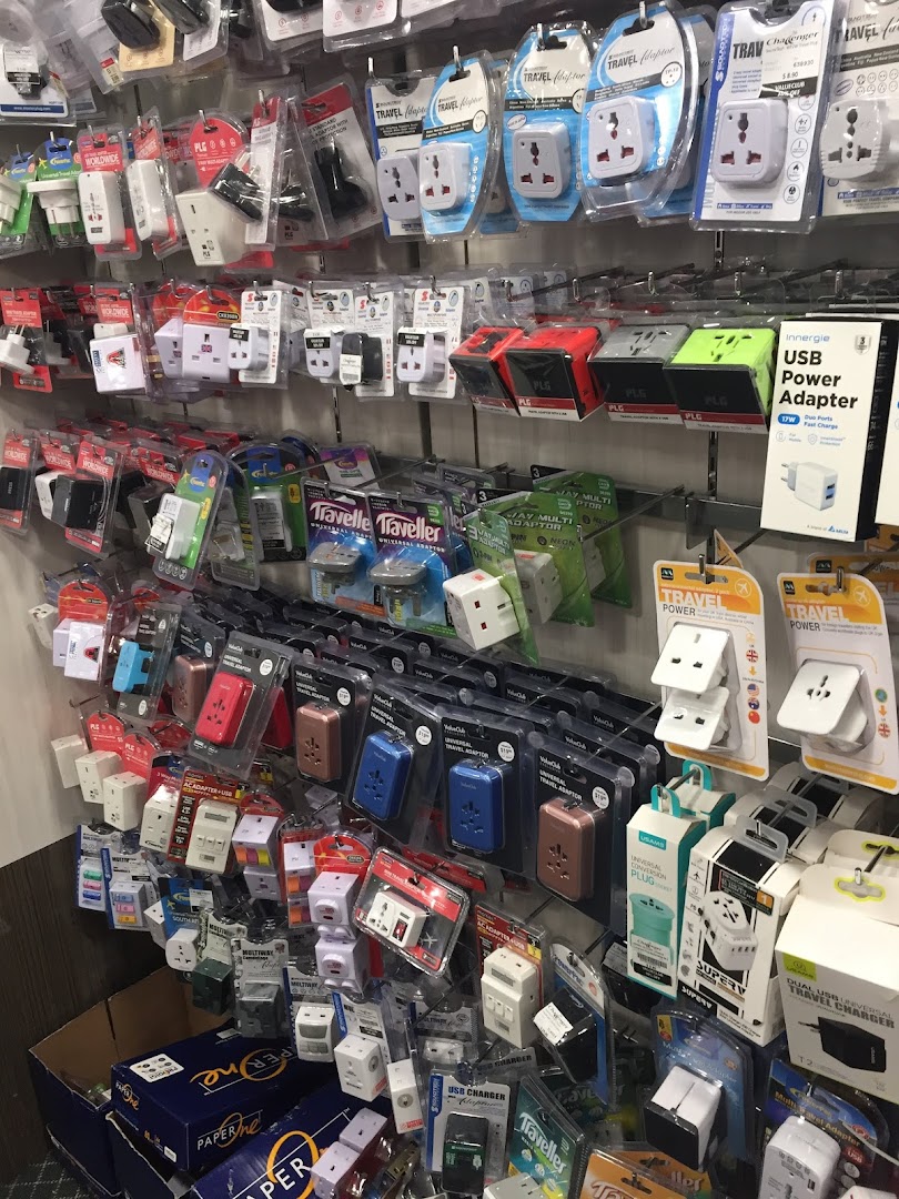 A wall display showcasing a wide variety of travel adapters, power adapters, and USB chargers.