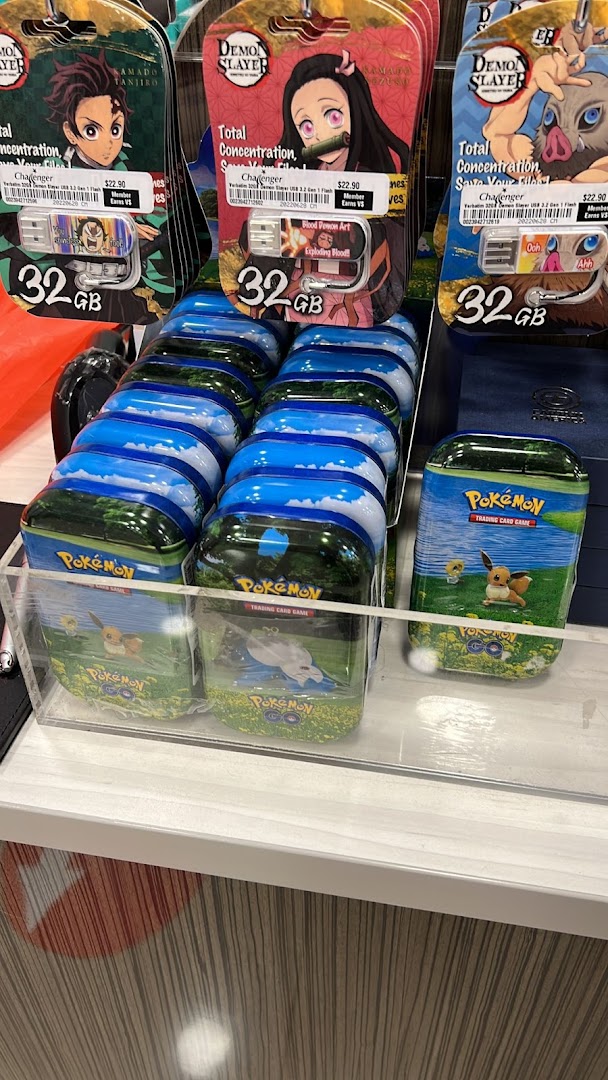 Close-up of anime-themed USB drives and Pokémon trading card game tins displayed at Challenger.