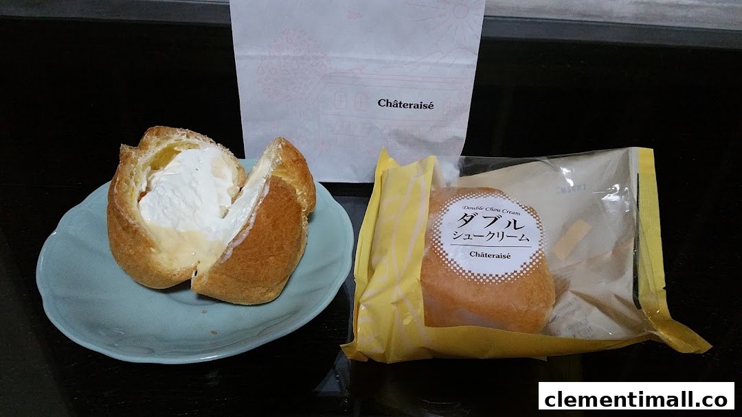 Two Châteraisé cream puffs, one opened on a plate, alongside a branded paper bag.