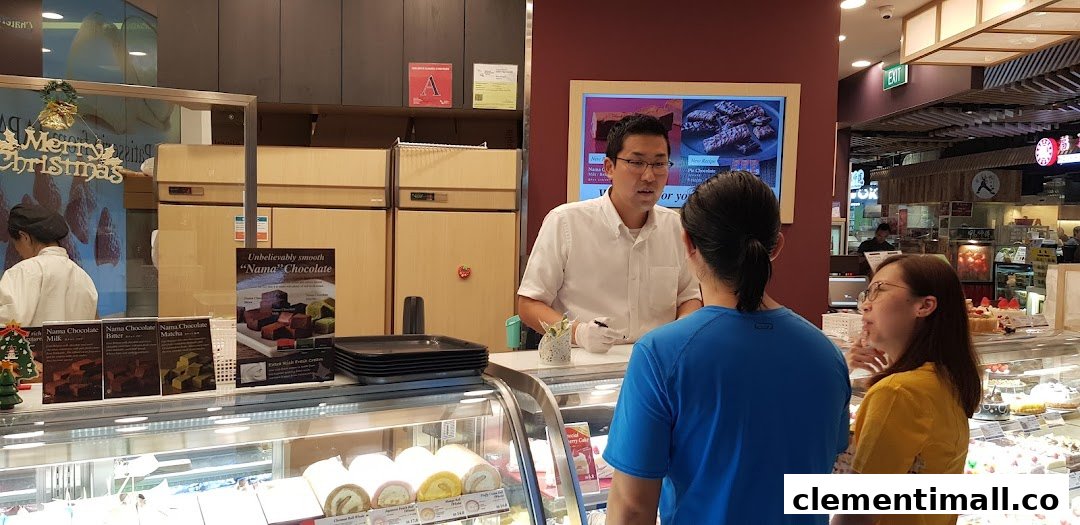 Châteraisé staff assist customers at a vibrant dessert counter displaying cakes, rolls, and chocolates.