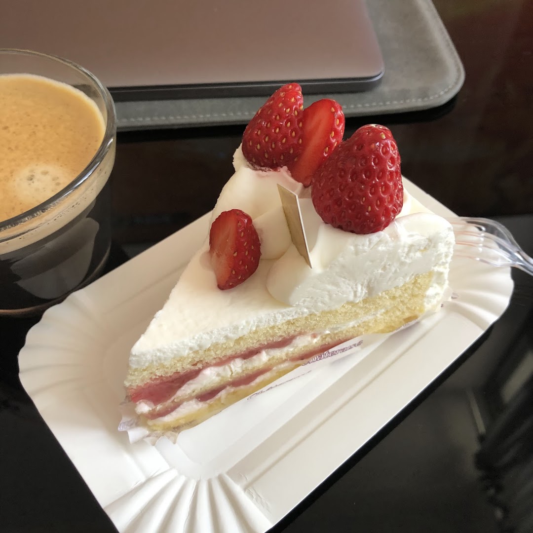 A delicious slice of strawberry shortcake with fresh strawberries and cream, served with a cup of coffee.