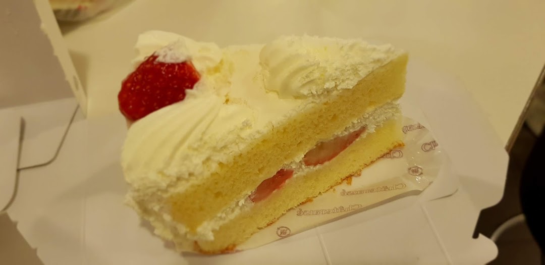 A delicious slice of strawberry shortcake with cream and fresh strawberries in a box.