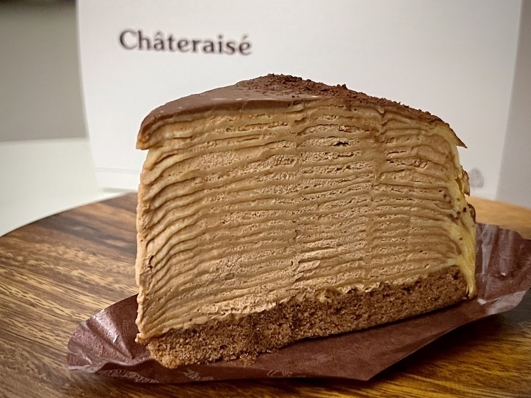 A delicious slice of chocolate mille crepe cake from Châteraisé on a wooden board.