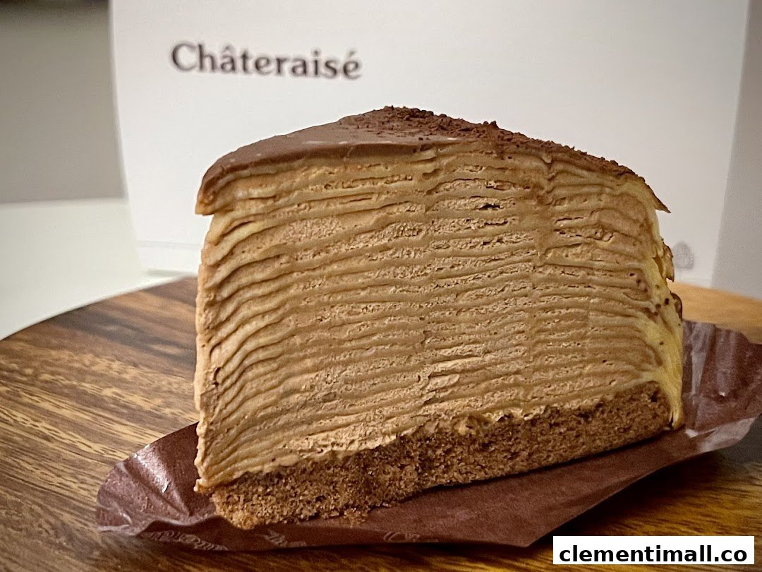 A delicious slice of chocolate mille crepe cake from Châteraisé on a wooden board.