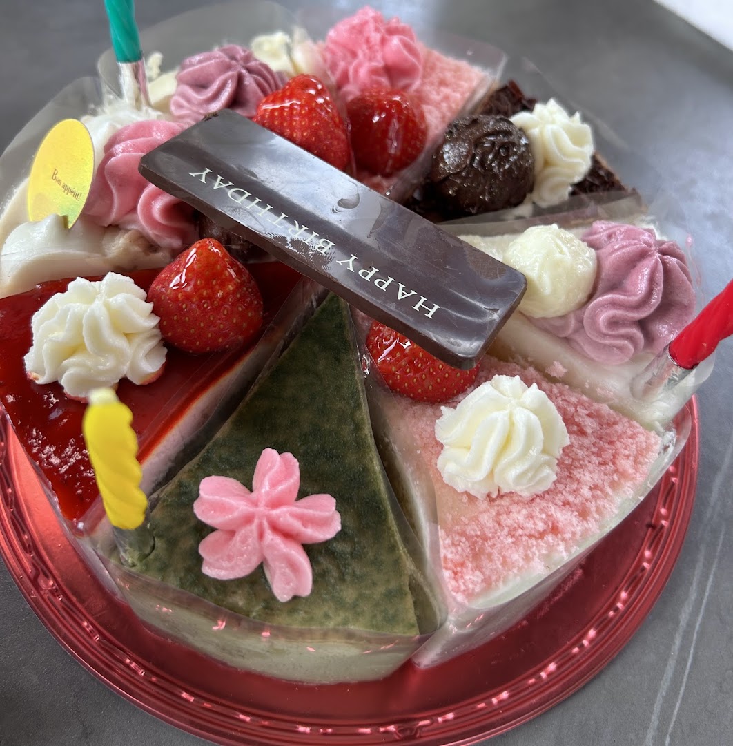 A vibrant assortment of cake slices forming a whole cake, adorned with fruits, cream, and a 'Happy Birthday' chocolate.