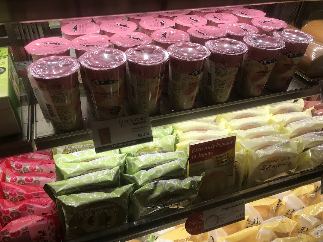 A refrigerated display case showcasing a variety of Japanese desserts and beverages, including smoothies and cream rolls.