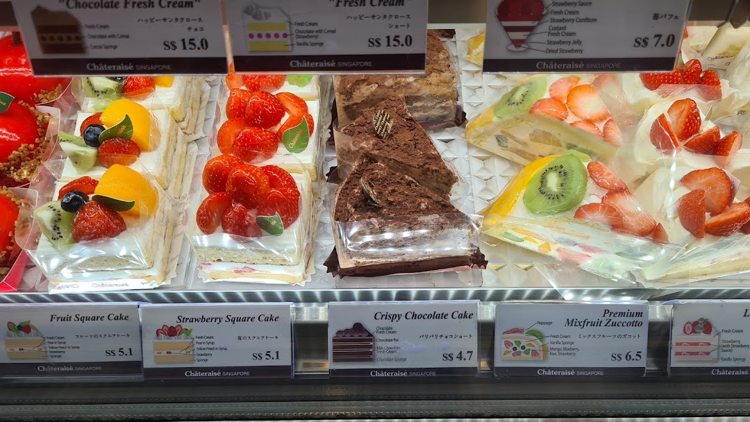 A vibrant display case showcasing various delicious cakes and desserts with price tags.