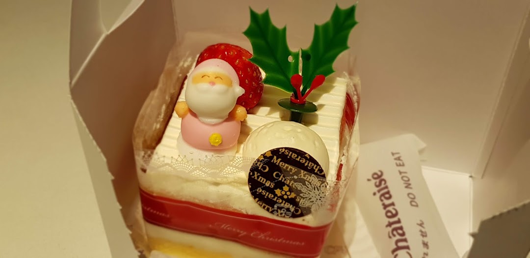 A festive Christmas cake from Châteraisé, adorned with Santa, strawberry, and holly decorations.