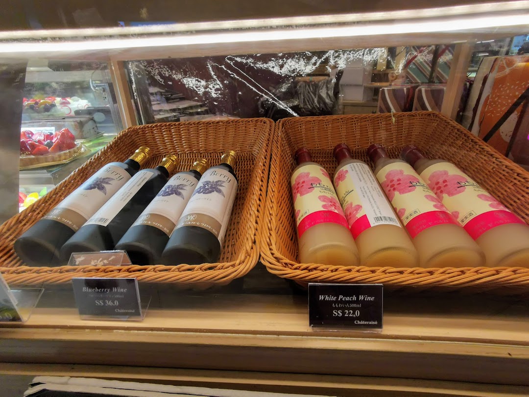 Bottles of Blueberry and White Peach Wine displayed in baskets with price tags at Châteraisé.