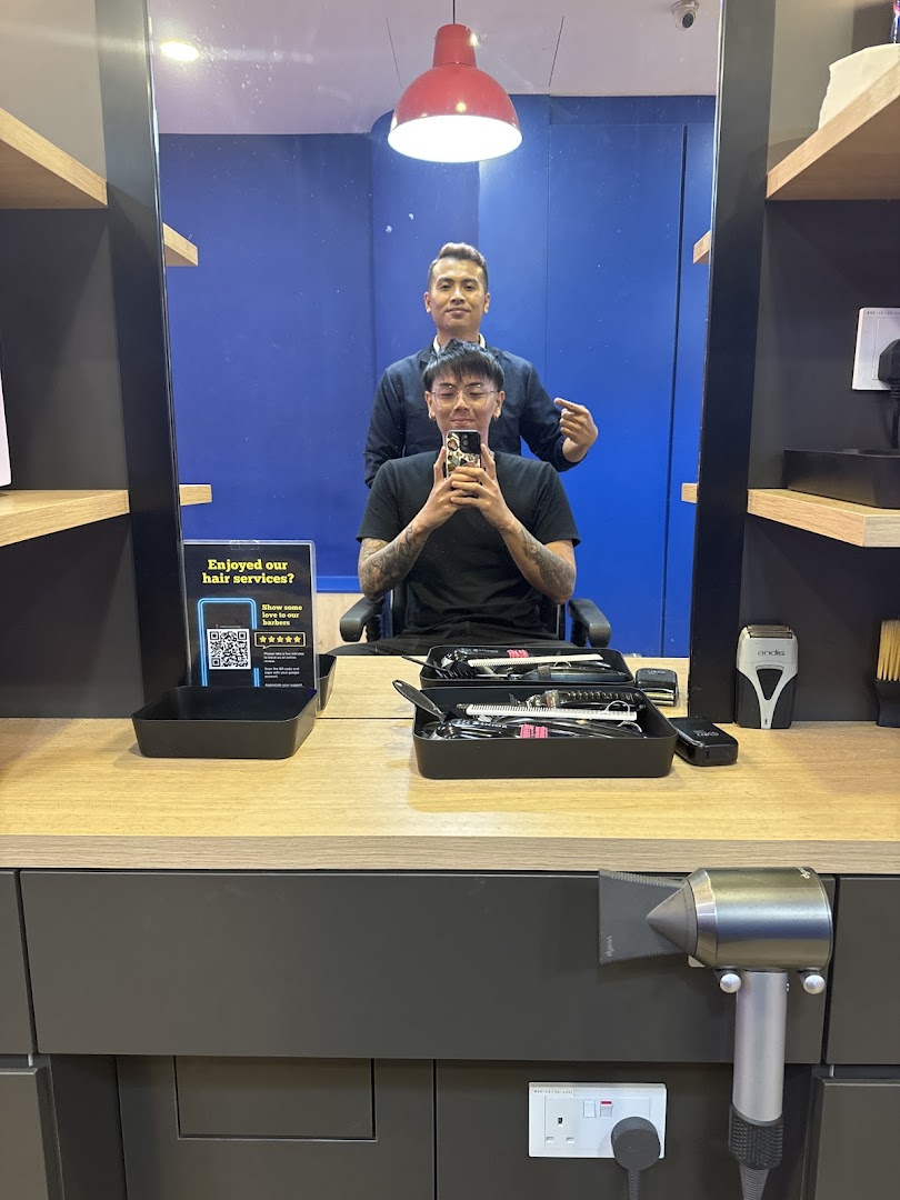 A customer takes a selfie with a barber in the mirror reflection at Clippers Barber.