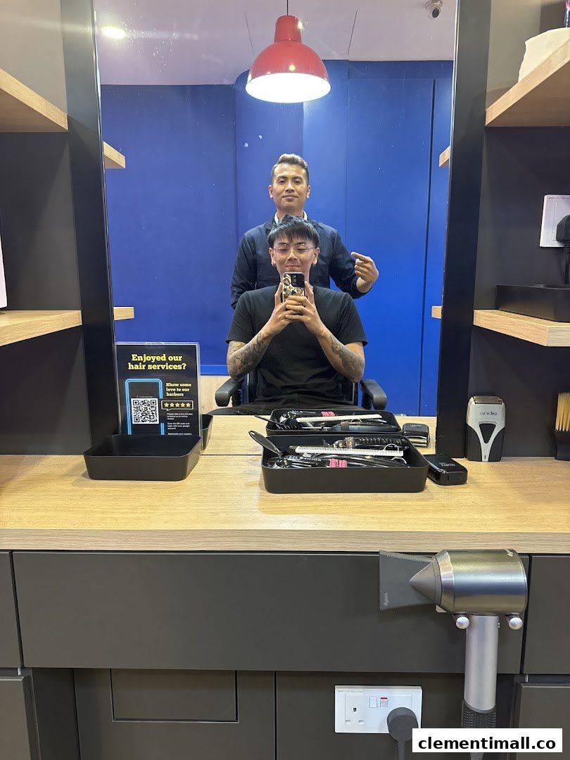 A customer takes a selfie with a barber in the mirror reflection at Clippers Barber.
