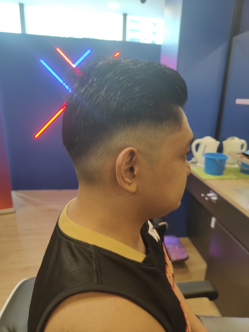 A customer showcasing a fresh fade haircut with stylish neon lighting in the background at Clippers Barber.