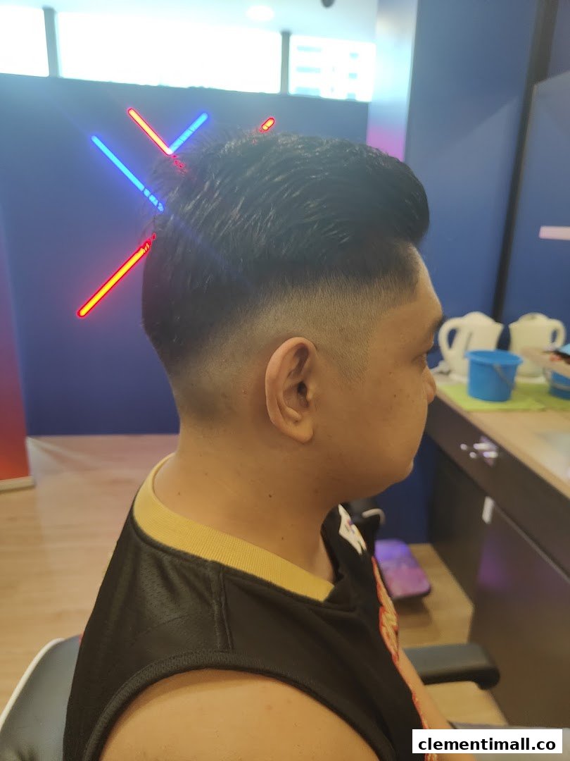 A customer showcasing a fresh fade haircut with stylish neon lighting in the background at Clippers Barber.