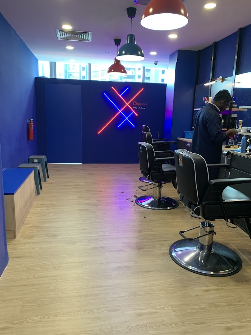 Interior view of Clippers Barber with modern chairs, a vibrant neon sign, and a barber at work.