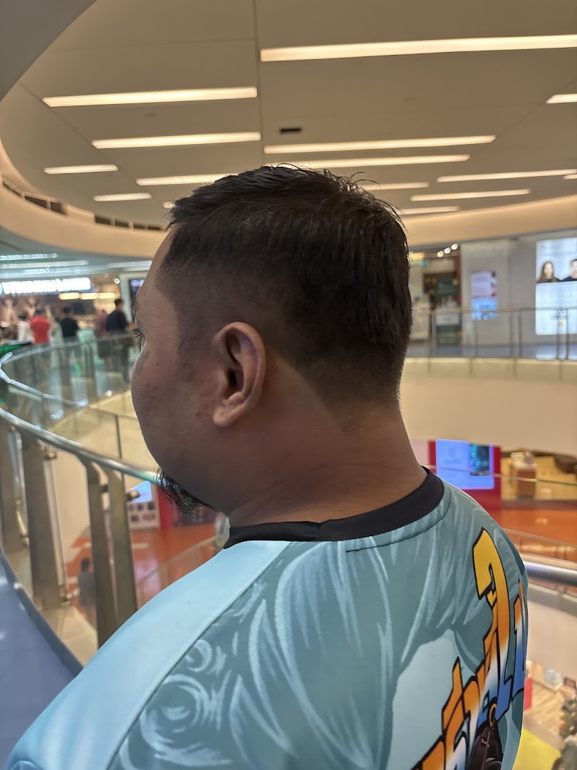 A person with a fresh haircut, showcasing a fade, looking out into a bustling mall.