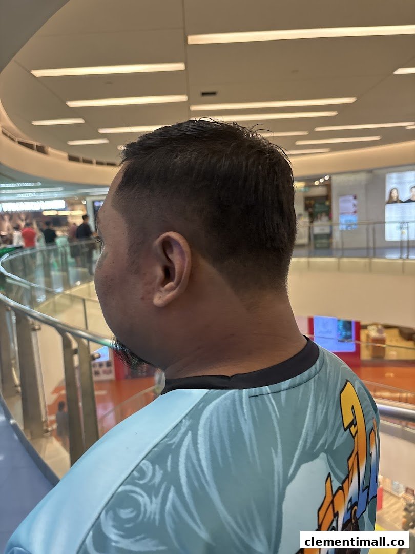 A person with a fresh haircut, showcasing a fade, looking out into a bustling mall.