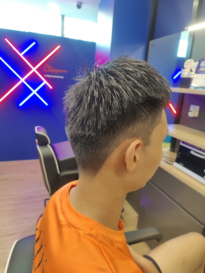 A customer showcases a fresh haircut inside Clippers Barber, featuring modern neon decor.