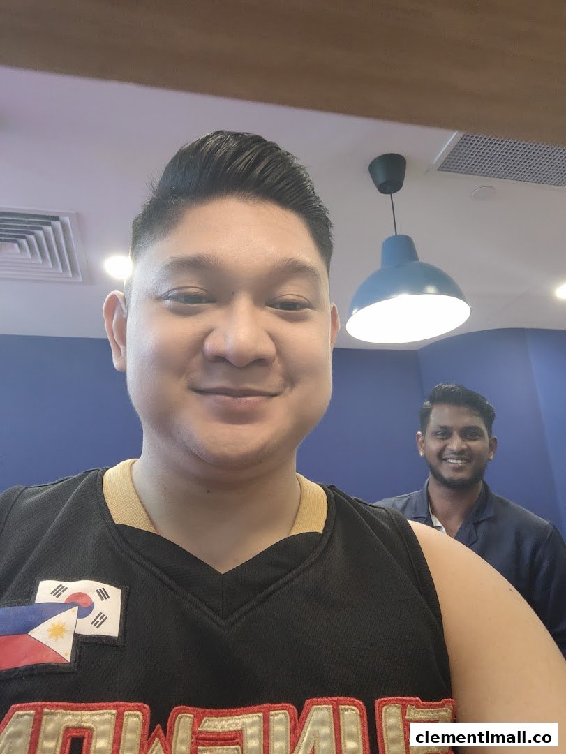 Two smiling men inside Clippers Barber, one in the foreground with a fresh haircut.