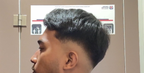 A close-up of a man showcasing a fresh, stylish haircut with a clean fade.