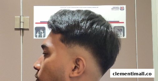 A close-up of a man showcasing a fresh, stylish haircut with a clean fade.