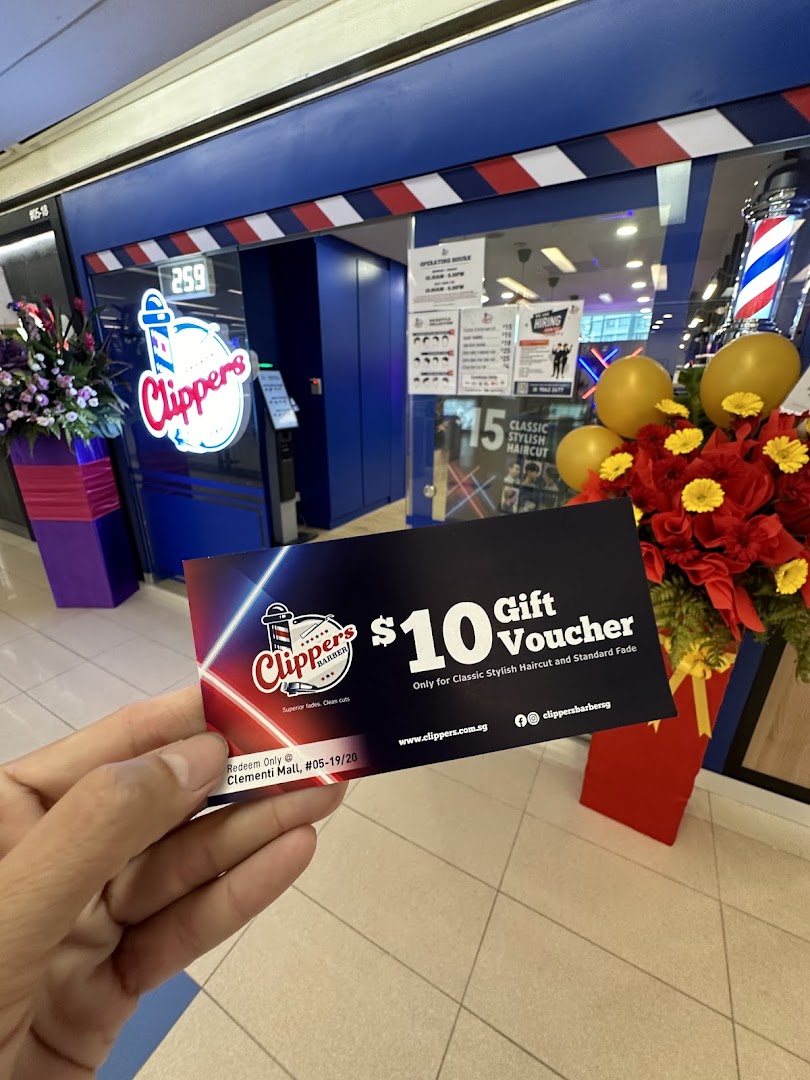 A hand holds a $10 gift voucher in front of Clippers Barber shop entrance at Clementi Mall.