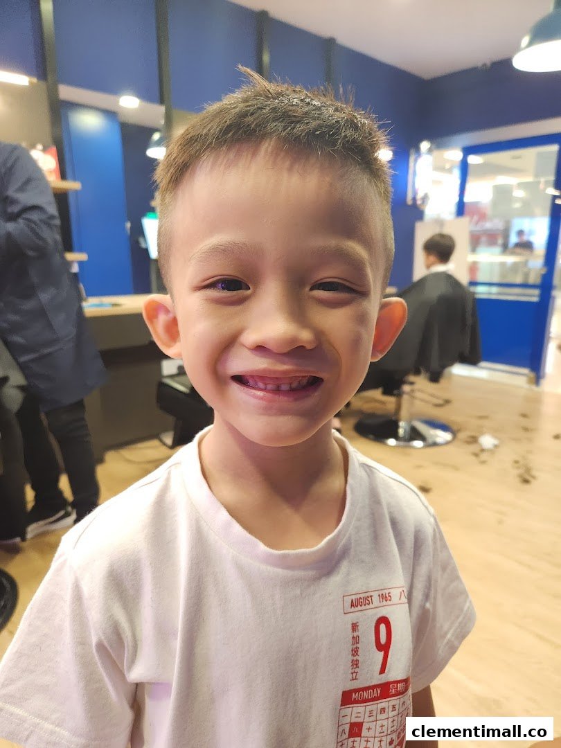 A happy child smiles after a fresh haircut inside Clippers Barber, showcasing a family-friendly atmosphere.