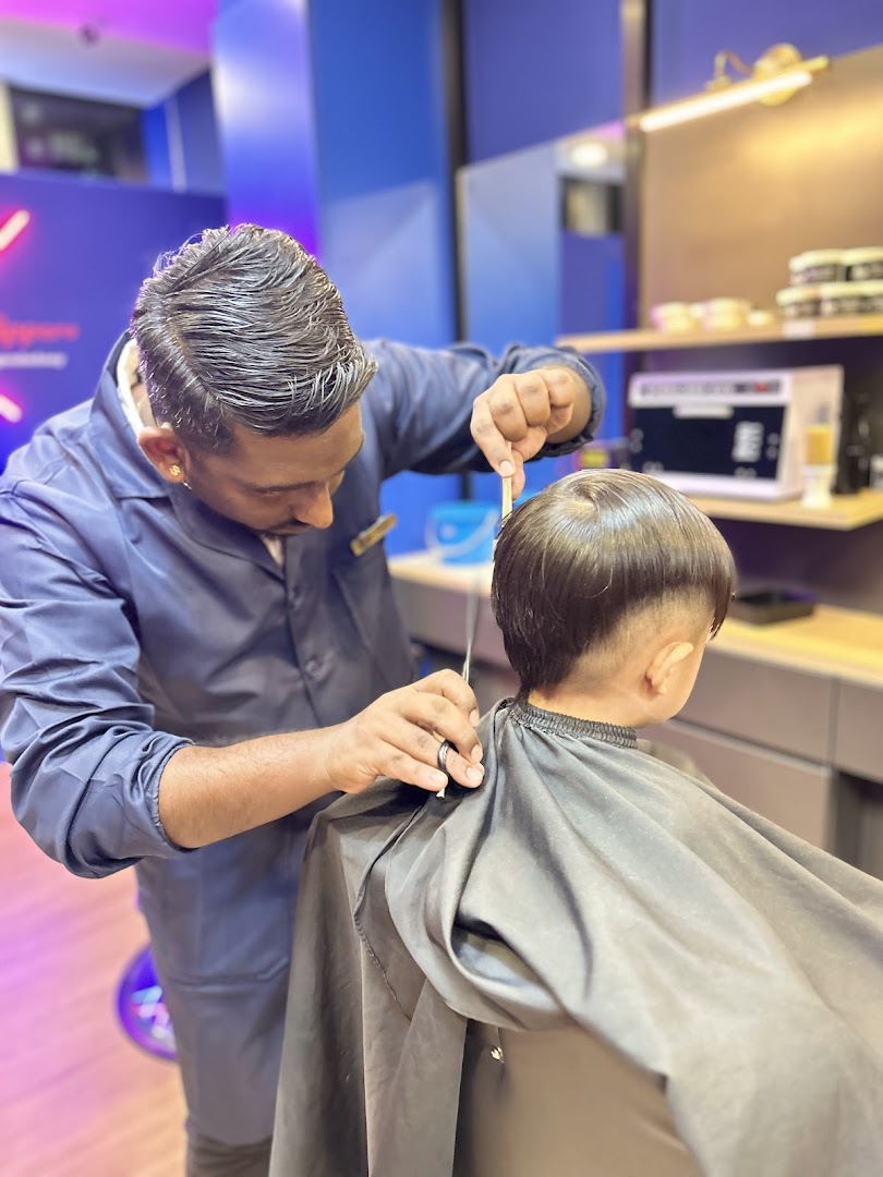 A skilled barber meticulously cutting a child's hair inside Clippers Barber.