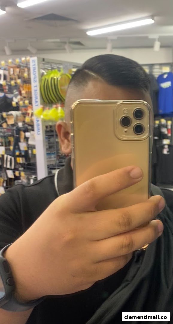 A person takes a selfie, showcasing a fresh haircut with a retail store background.