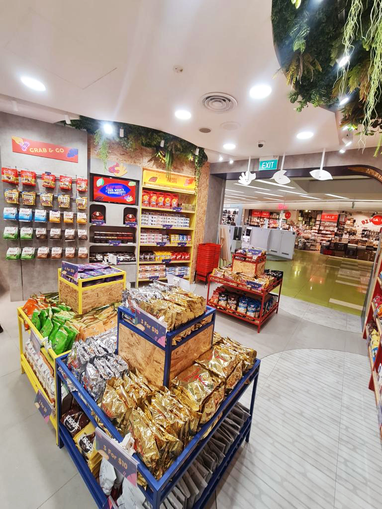 An interior view of Cocoa Pods by The Cocoa Trees, showcasing shelves filled with packaged snacks and chocolates.