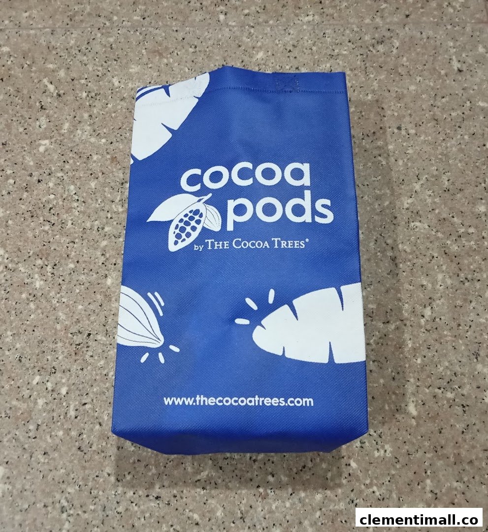 A blue shopping bag featuring the 'Cocoa Pods by The Cocoa Trees' logo and website.