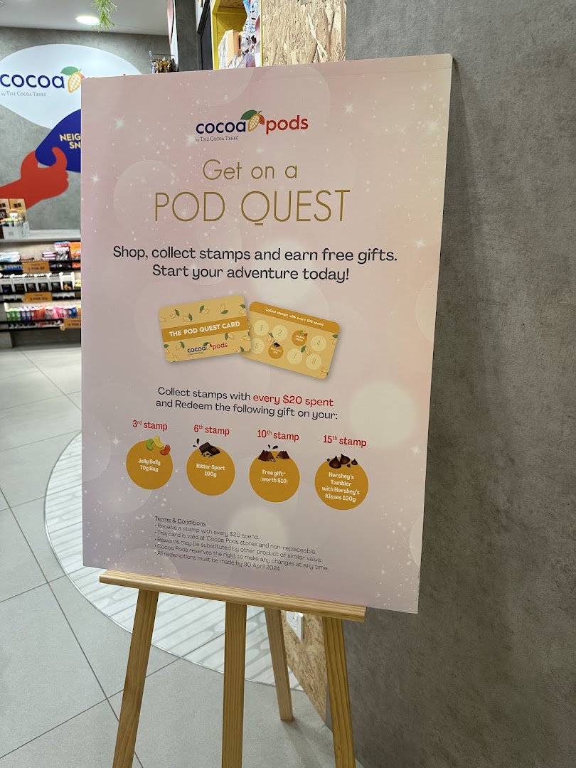 A promotional standee for Cocoa Pods' 'Pod Quest' loyalty program, detailing stamp collection and rewards.