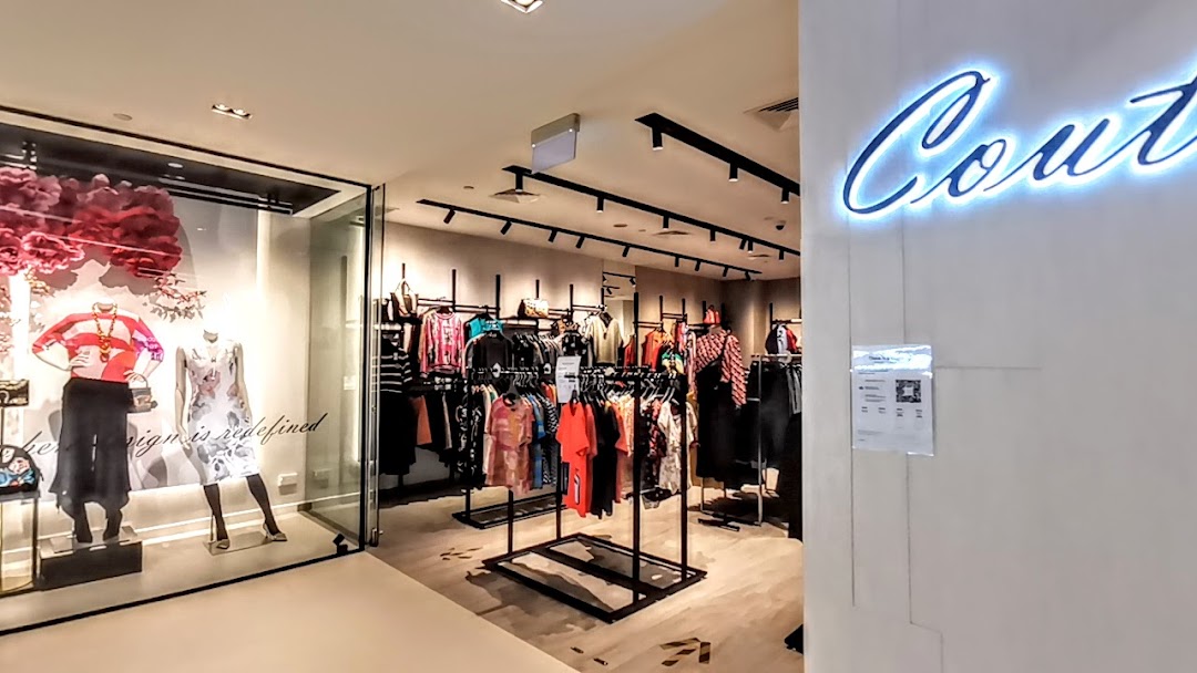 Interior view of Couture by Szan, showcasing mannequins in the window and racks of stylish clothing.