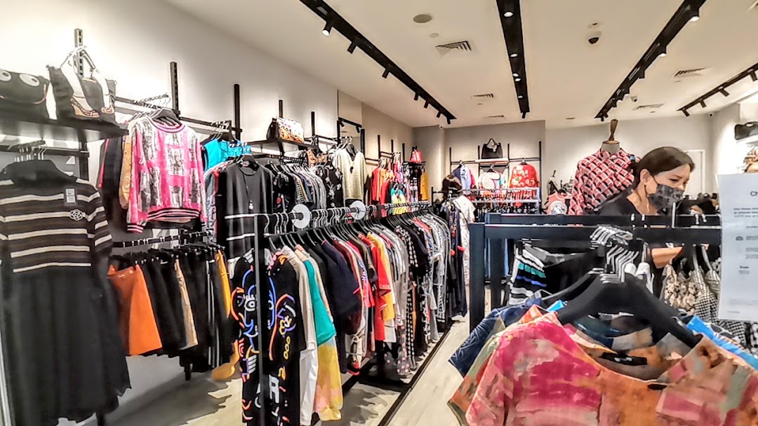 Interior view of Couture by Szan, showcasing diverse clothing racks, handbags, and a shopper browsing.