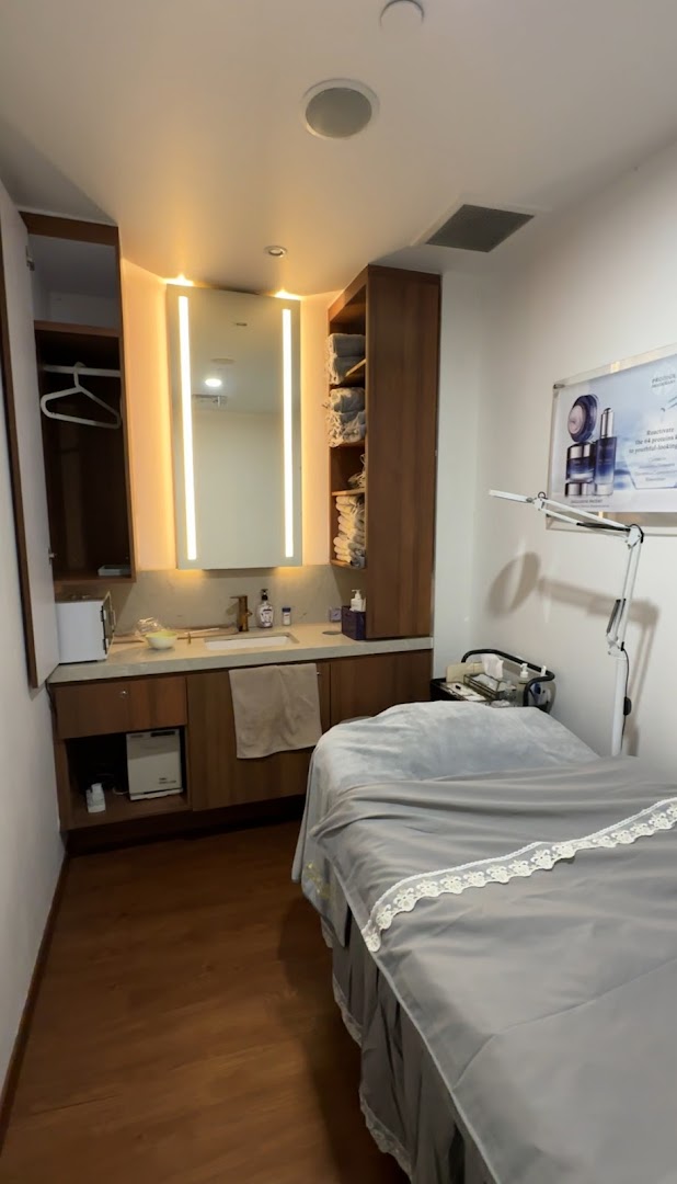 A clean and well-equipped beauty treatment room with a bed, sink, and storage.