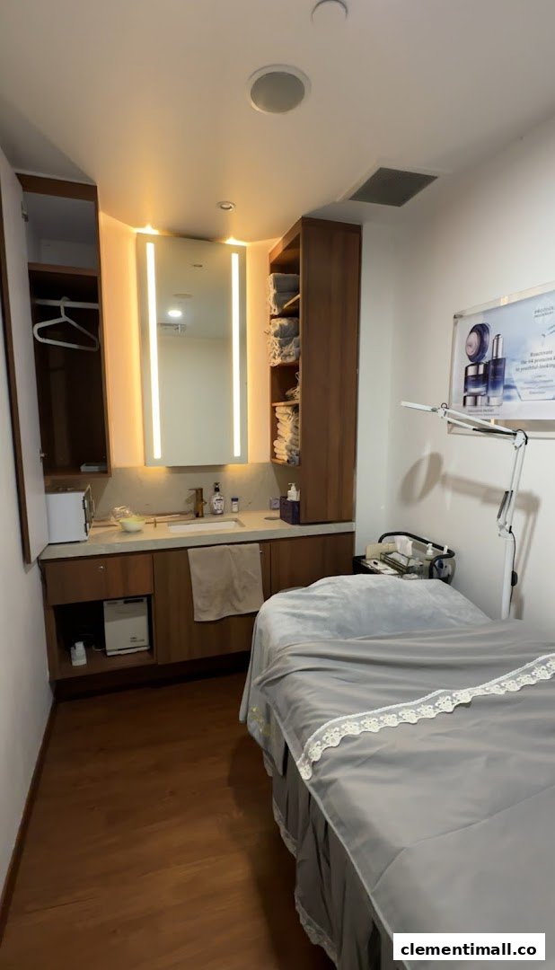 A clean and well-equipped beauty treatment room with a bed, sink, and storage.