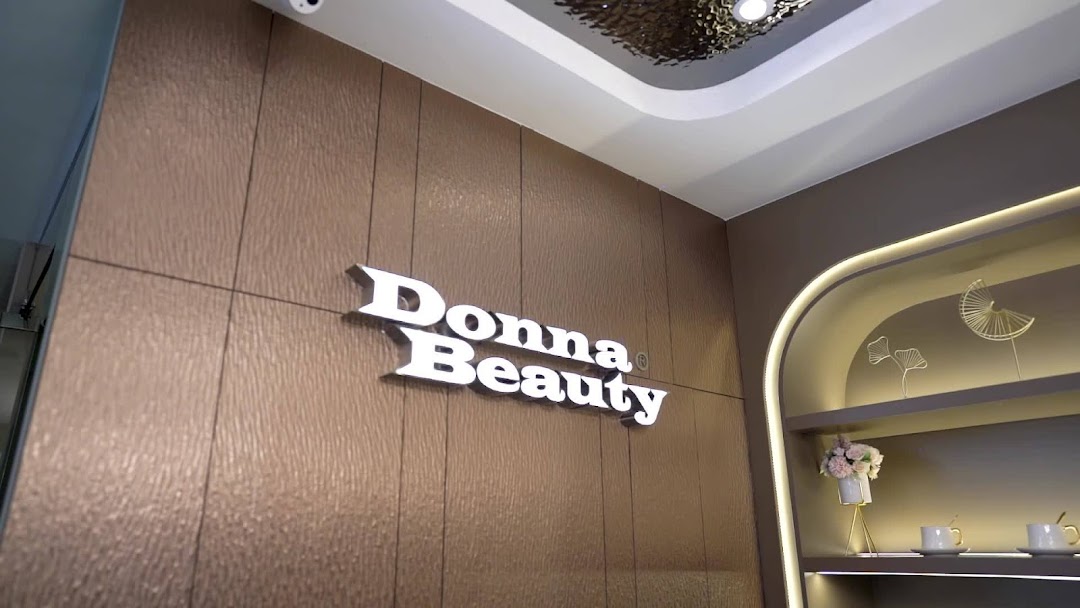 Interior view of Donna Beauty featuring its illuminated logo on a textured wall and decorative shelving.