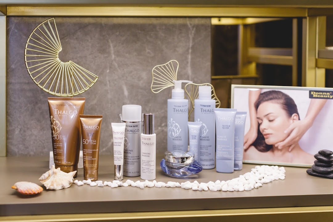 A display of Thalgo beauty products, including skincare and sun protection, with decorative elements like seashells and a framed image.
