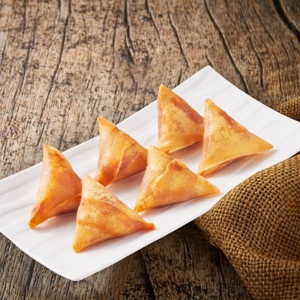 Six golden-brown triangular pastries, possibly samosas or spring rolls, arranged on a white rectangular plate.
