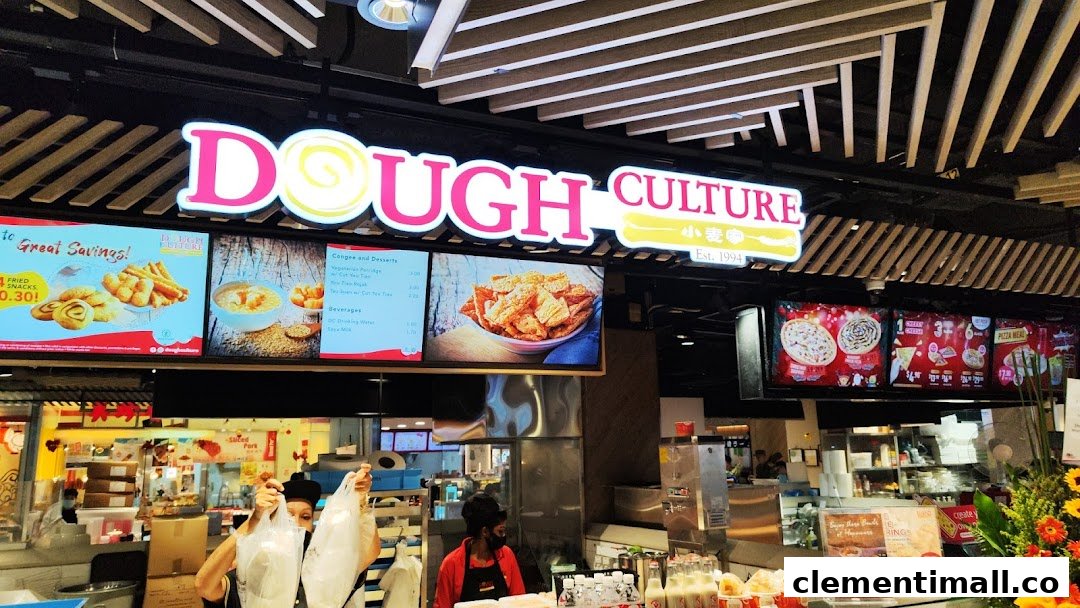 A bustling counter at Dough Culture with staff serving customers and digital menu displays.