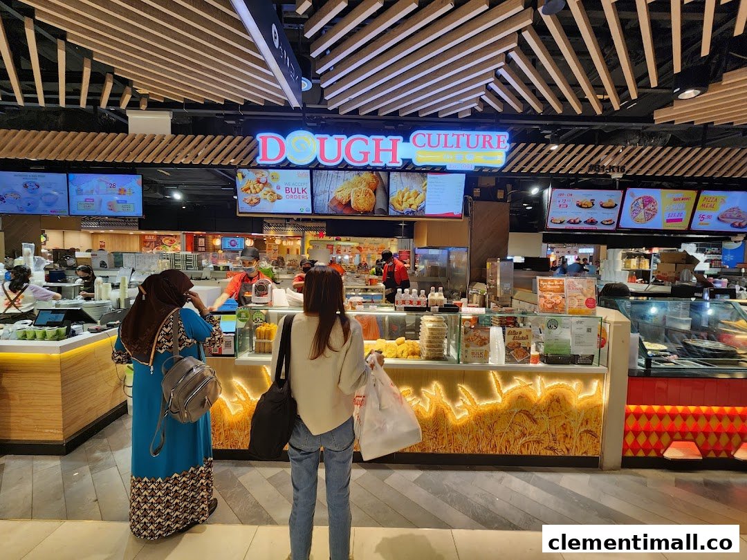 Customers at Dough Culture's counter, showcasing various baked goods and digital menu displays.