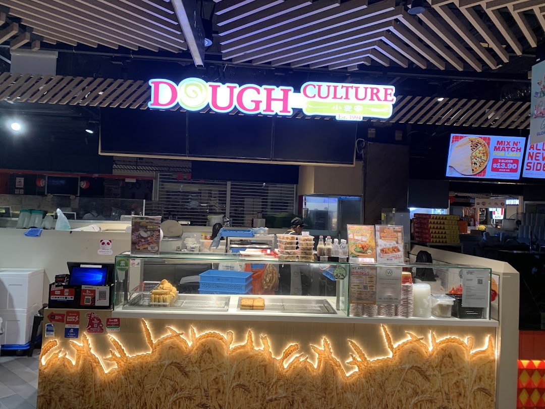 A vibrant counter display at Dough Culture, featuring its illuminated sign and fresh baked goods.
