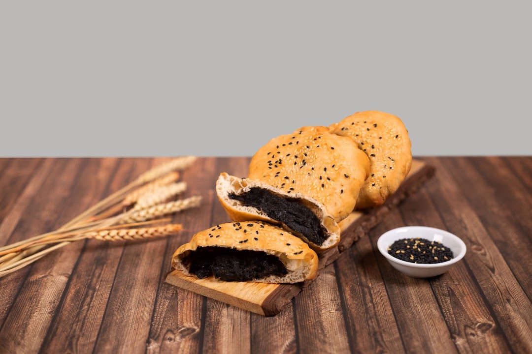 Golden pastries filled with black sesame paste, garnished with sesame seeds and wheat stalks.