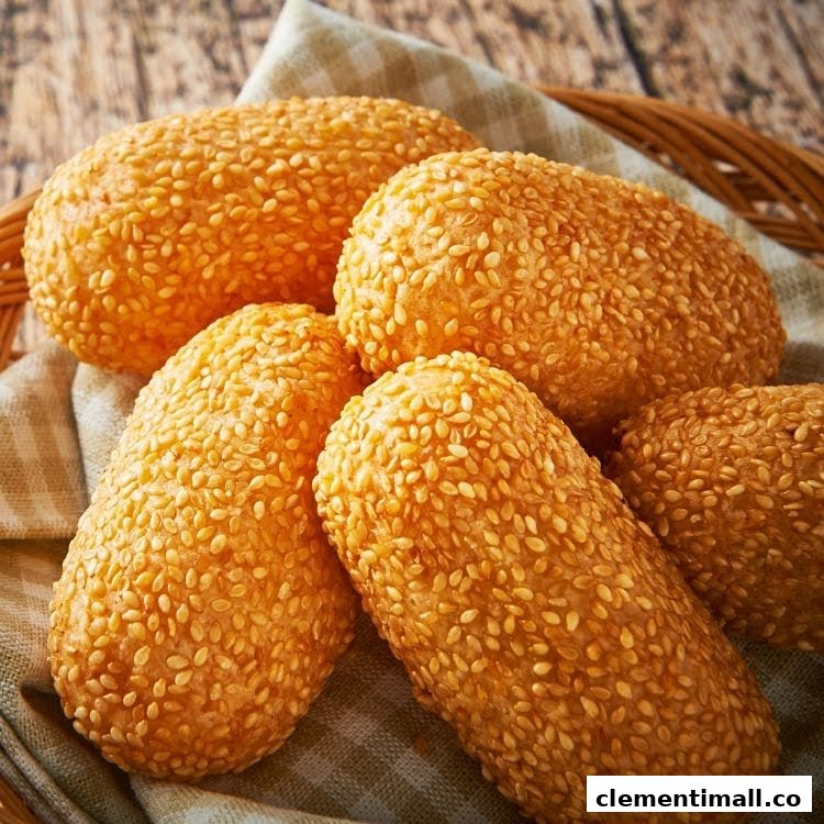 Close-up of golden-brown sesame-coated fried dough pastries in a basket.
