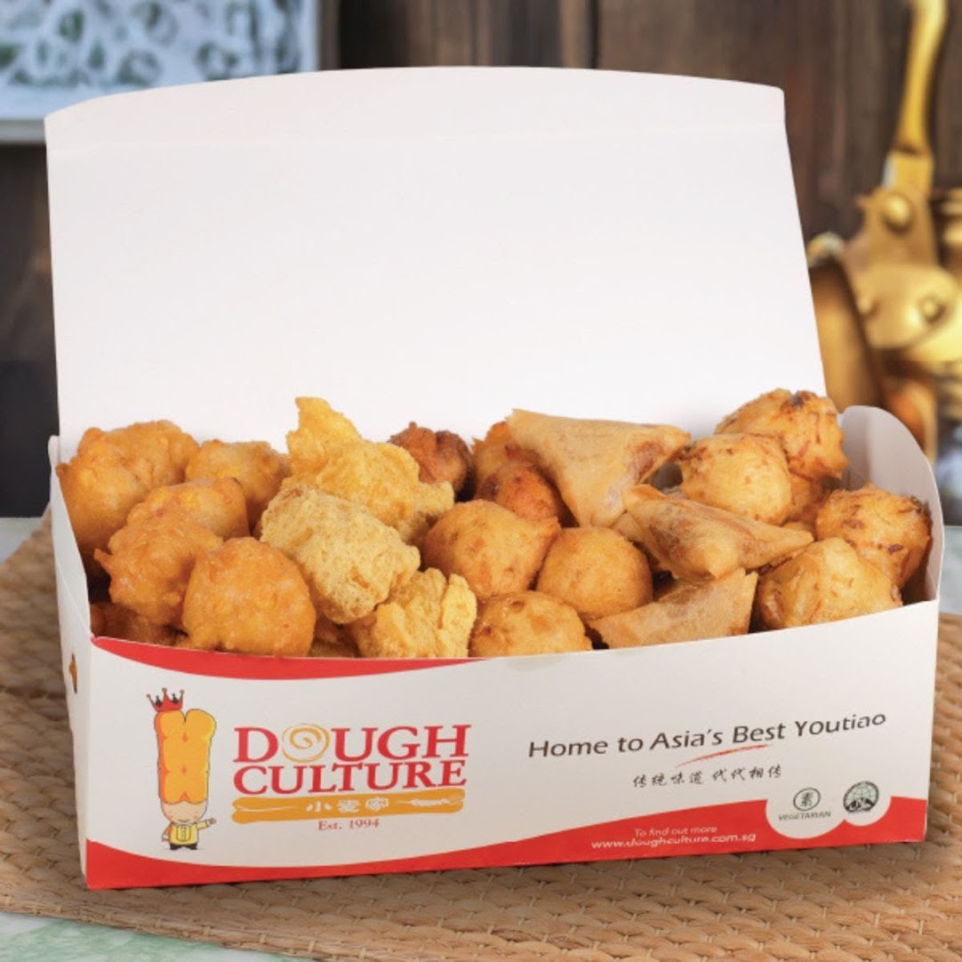 A box filled with various golden-fried snacks, including yew char kway and other delights, from Dough Culture.