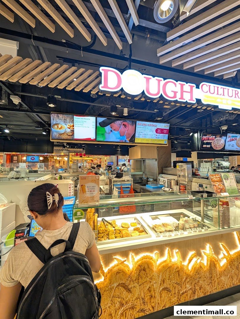 A customer at Dough Culture's counter, showcasing fresh pastries and digital menu screens.