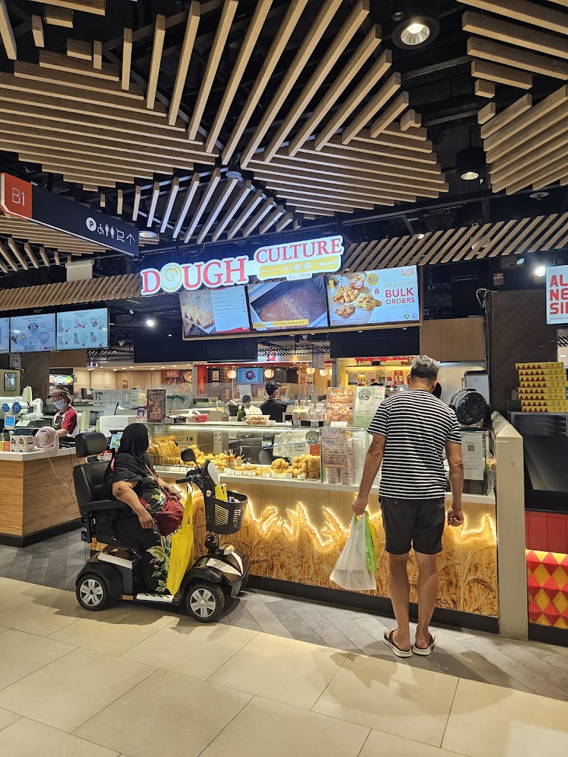 A bustling Dough Culture outlet with customers, showcasing a variety of fried dough products and a vibrant display.