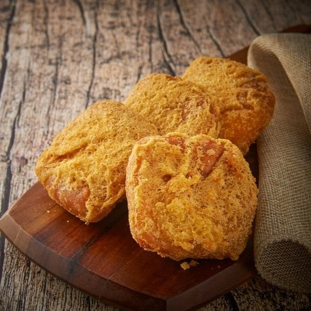 Several golden-brown fried dough pieces, possibly 'You Tiao' or similar, on a rustic wooden board.