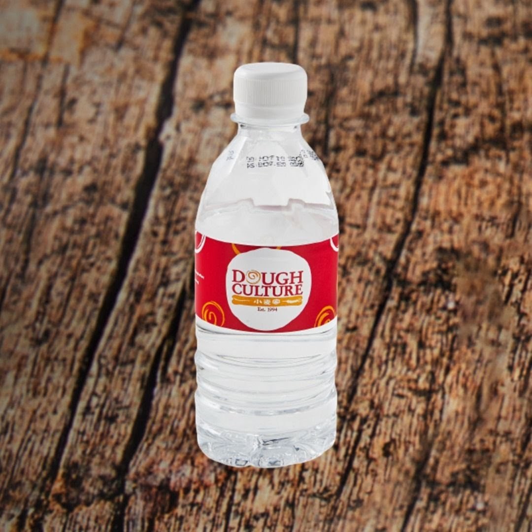 A Dough Culture branded water bottle with a red and white label on a wooden background.