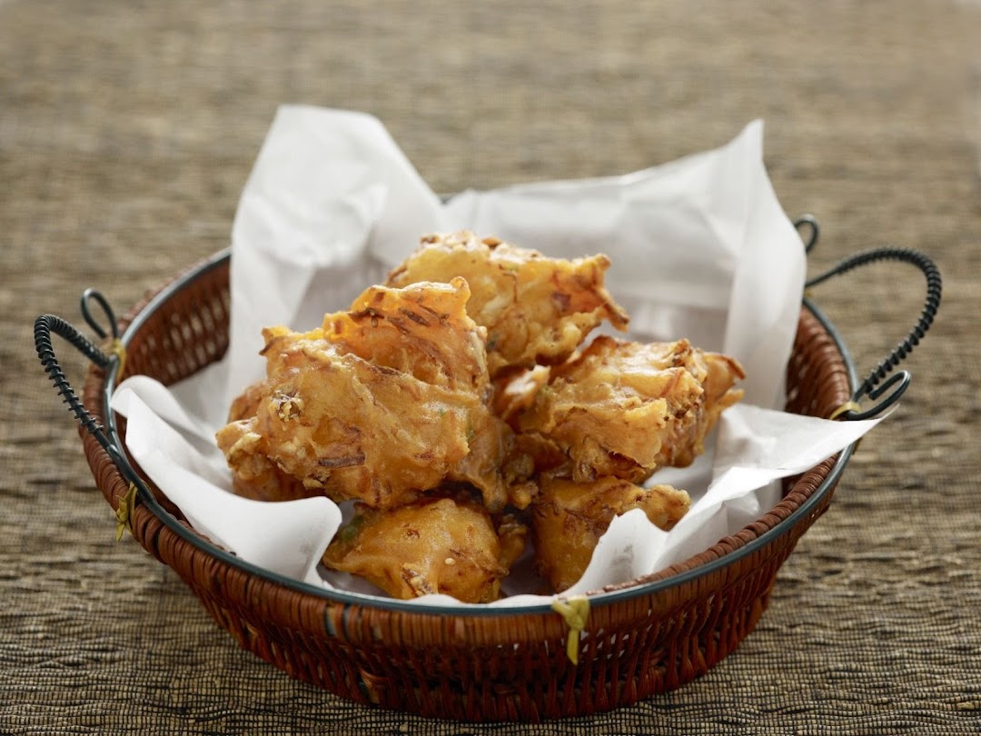 A basket of golden-brown fried dough fritters, served on white paper.